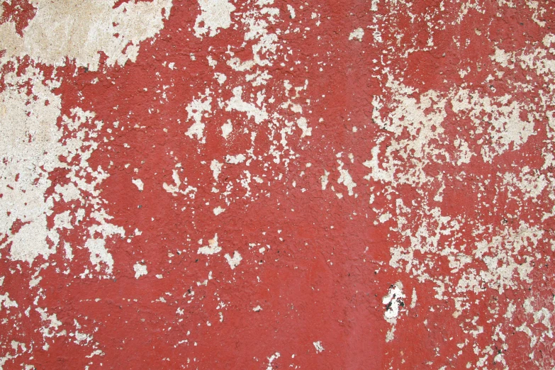 a close up of paint peeling off a red wall
