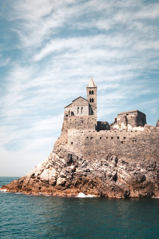 an island with a building on top of it and the ocean below