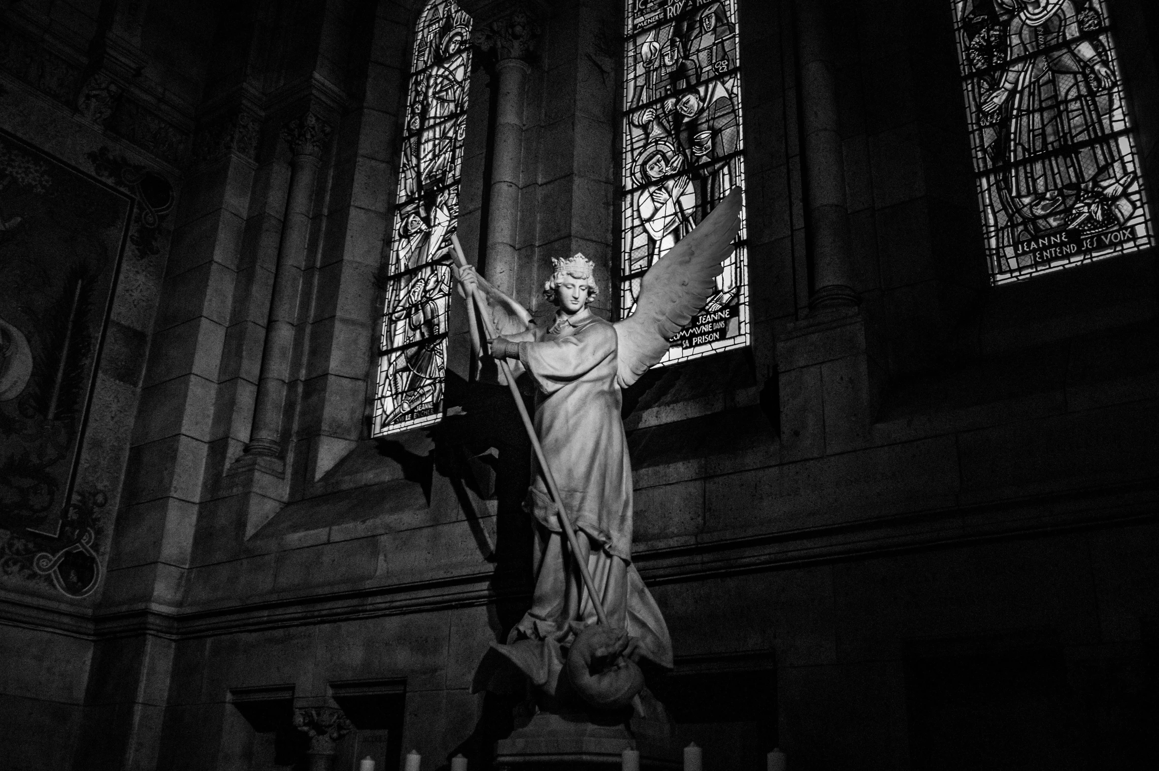 a statue stands in front of stained glass