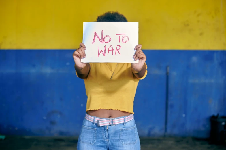 a young woman holding up a sign that says no to war