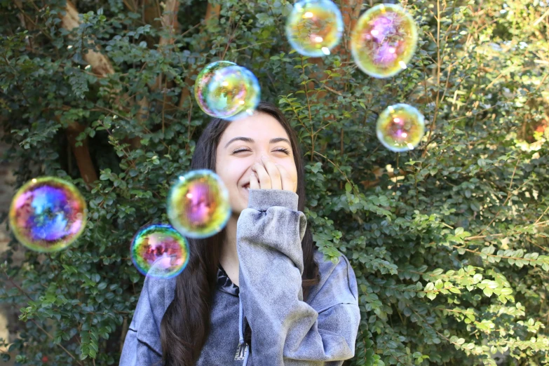 a girl looks up at soap bubbles floating in the air