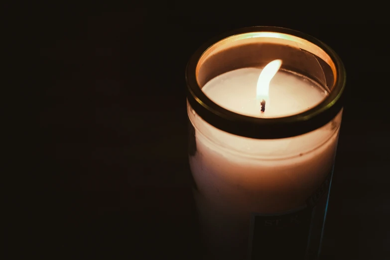 a lit candle is on top of a black surface