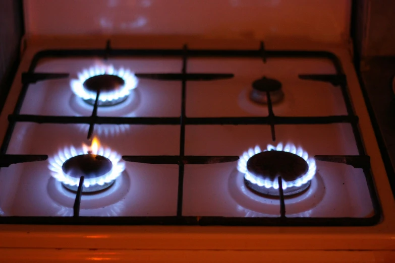 a stove with three burners cooking over it