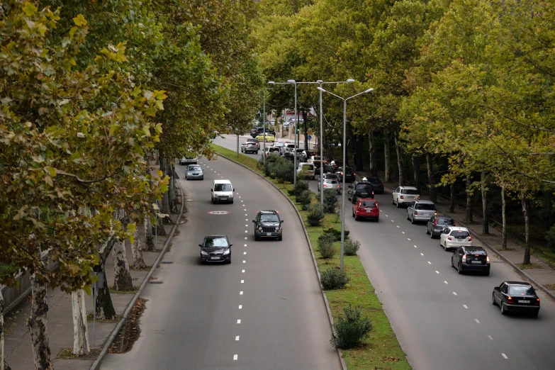 cars travel along a four lane road near an intersection