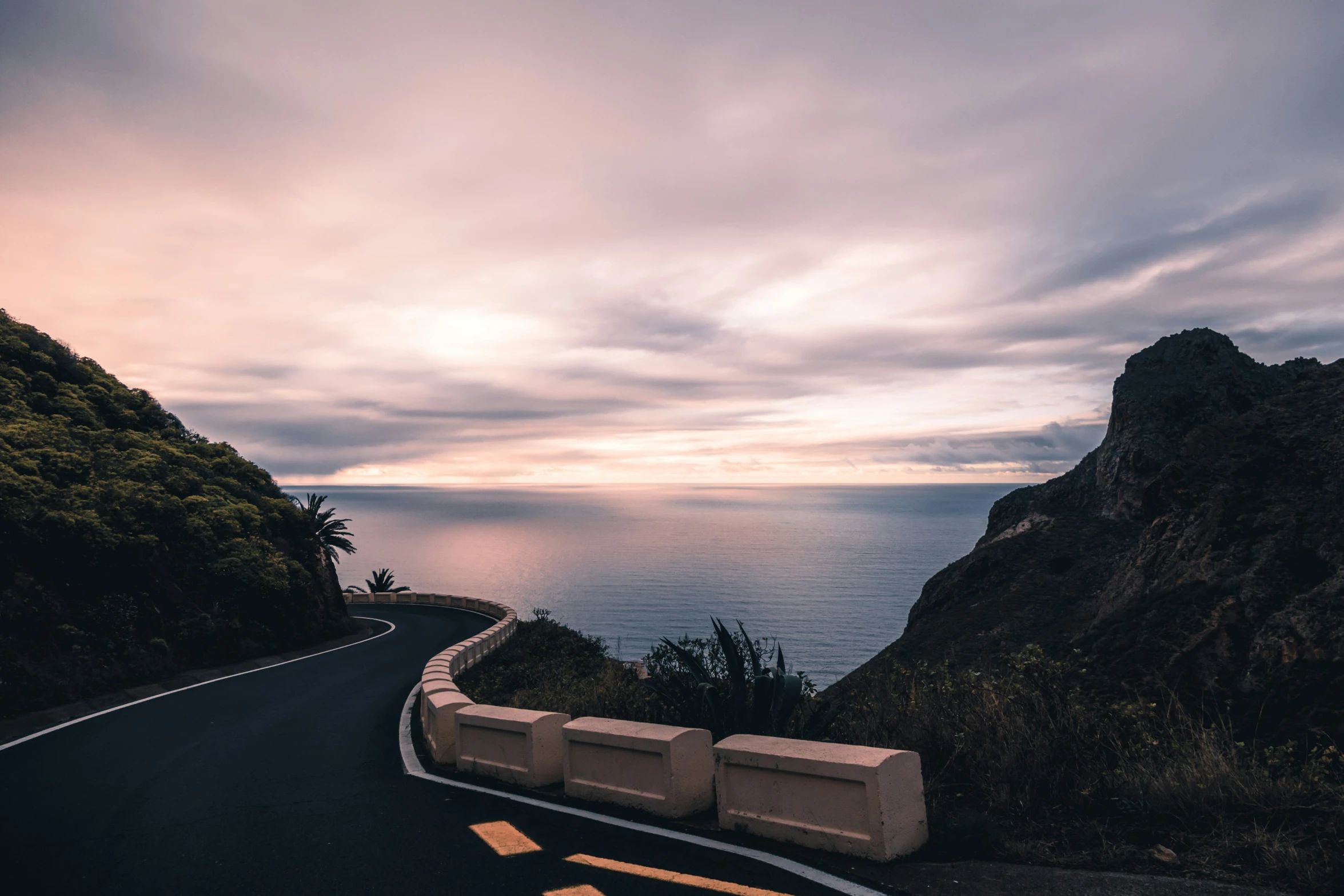 a highway running along side an ocean under cloudy skies