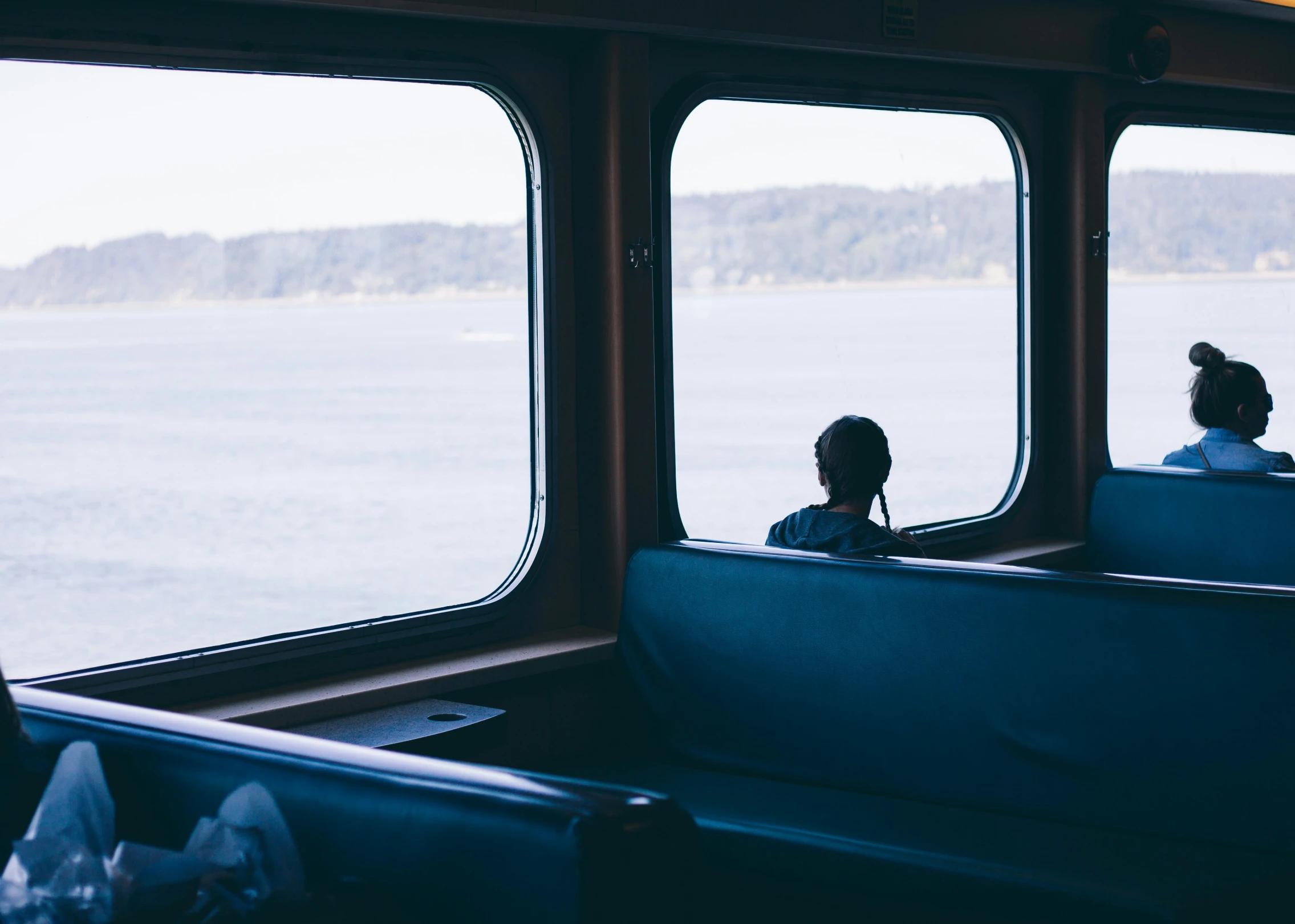 three people sitting at the windows overlooking the water