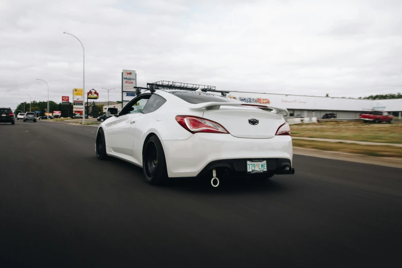 a white car driving on a street past an hyrdant store