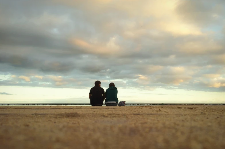 a couple sits on a beach looking out over the ocean