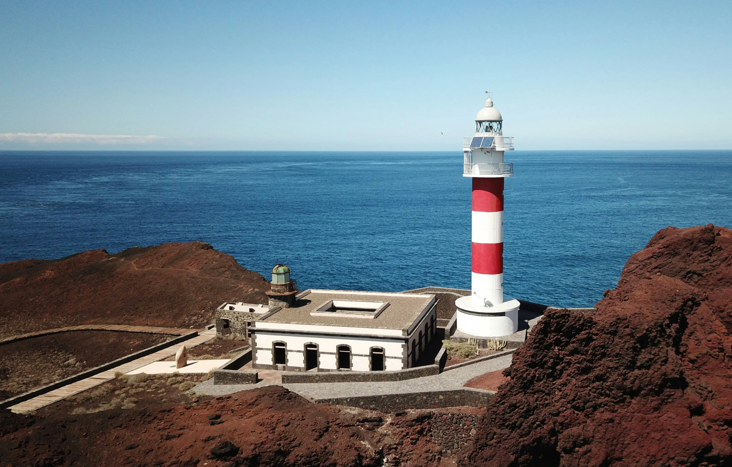 a lighthouse sits on a cliff near the water