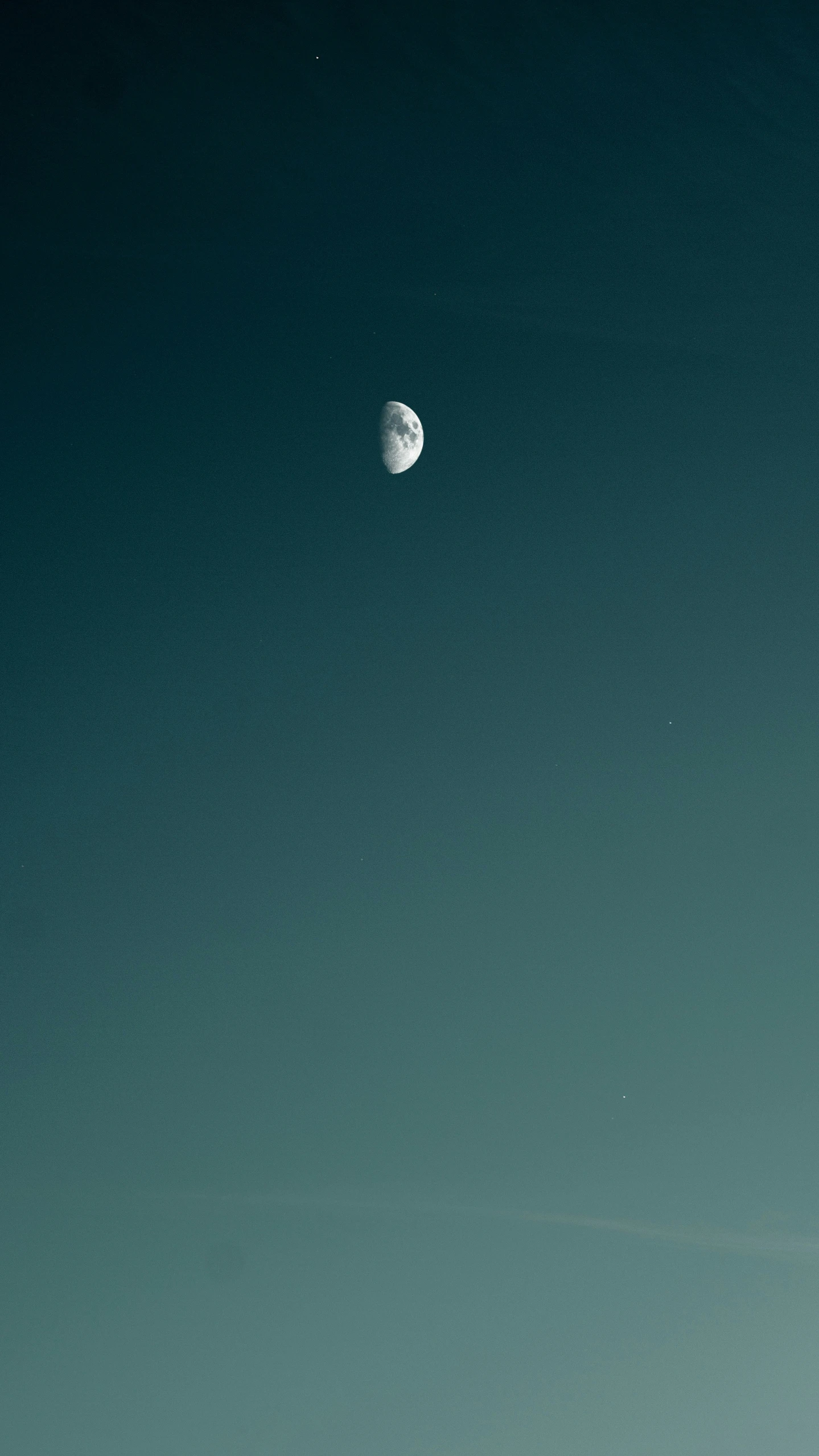 a boat is on the water and half moon in the distance