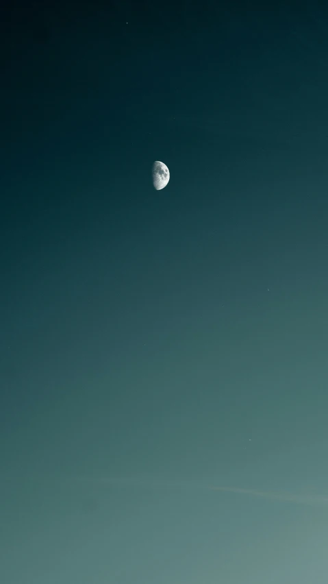 a boat is on the water and half moon in the distance