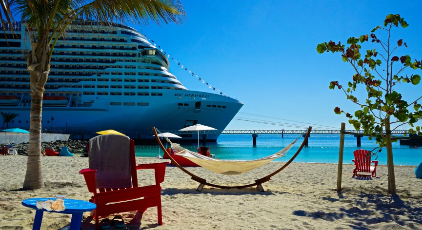 two red chairs and a hammock on the beach