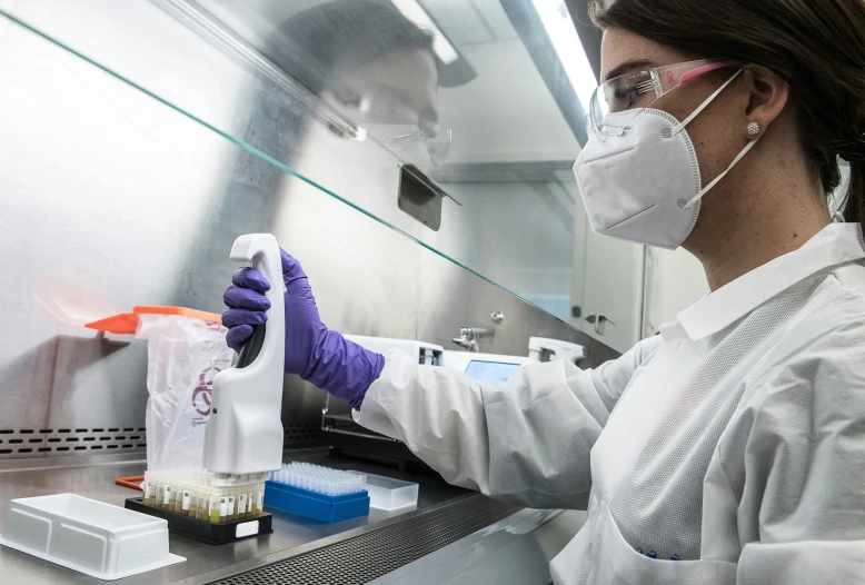 a woman wearing gloves and glasses uses a container