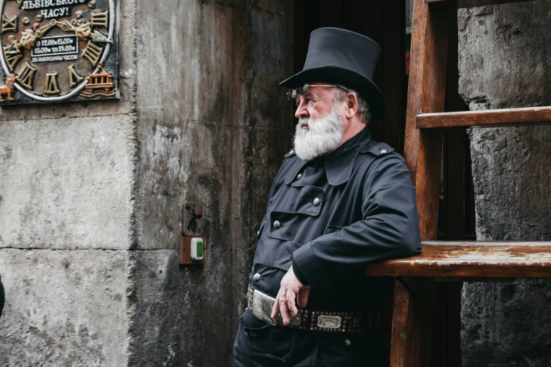 an old man with a goatee, standing on the steps looking down