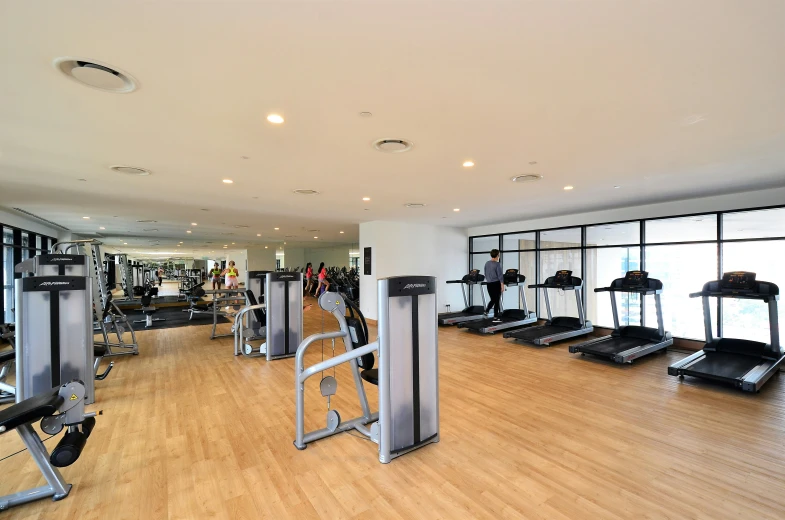 a gym with multiple machines and treadmills in the foreground