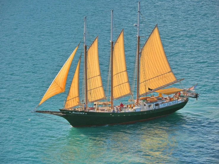 a large yellow sailboat floating in the ocean