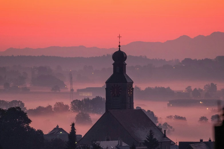 the silhouette of a church against an orange and pink sky