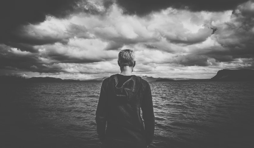 a man in the water staring at dark clouds