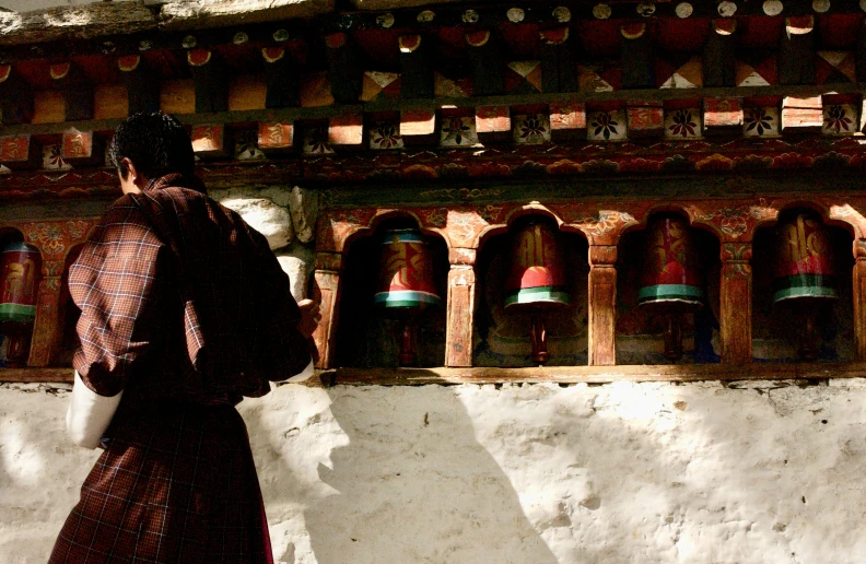 the woman is standing near a wall with bells in the background