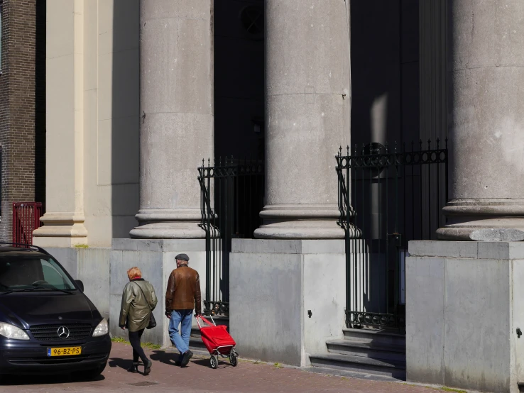 two people walking down the street and cars passing by