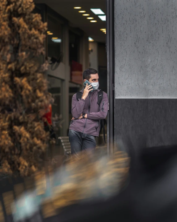 a man with a face mask is holding up his cell phone