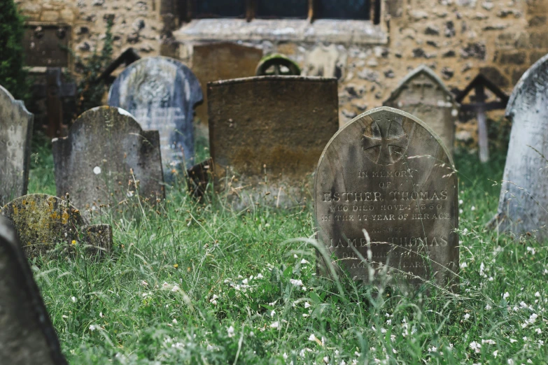 a bunch of headstones on some grass next to a building