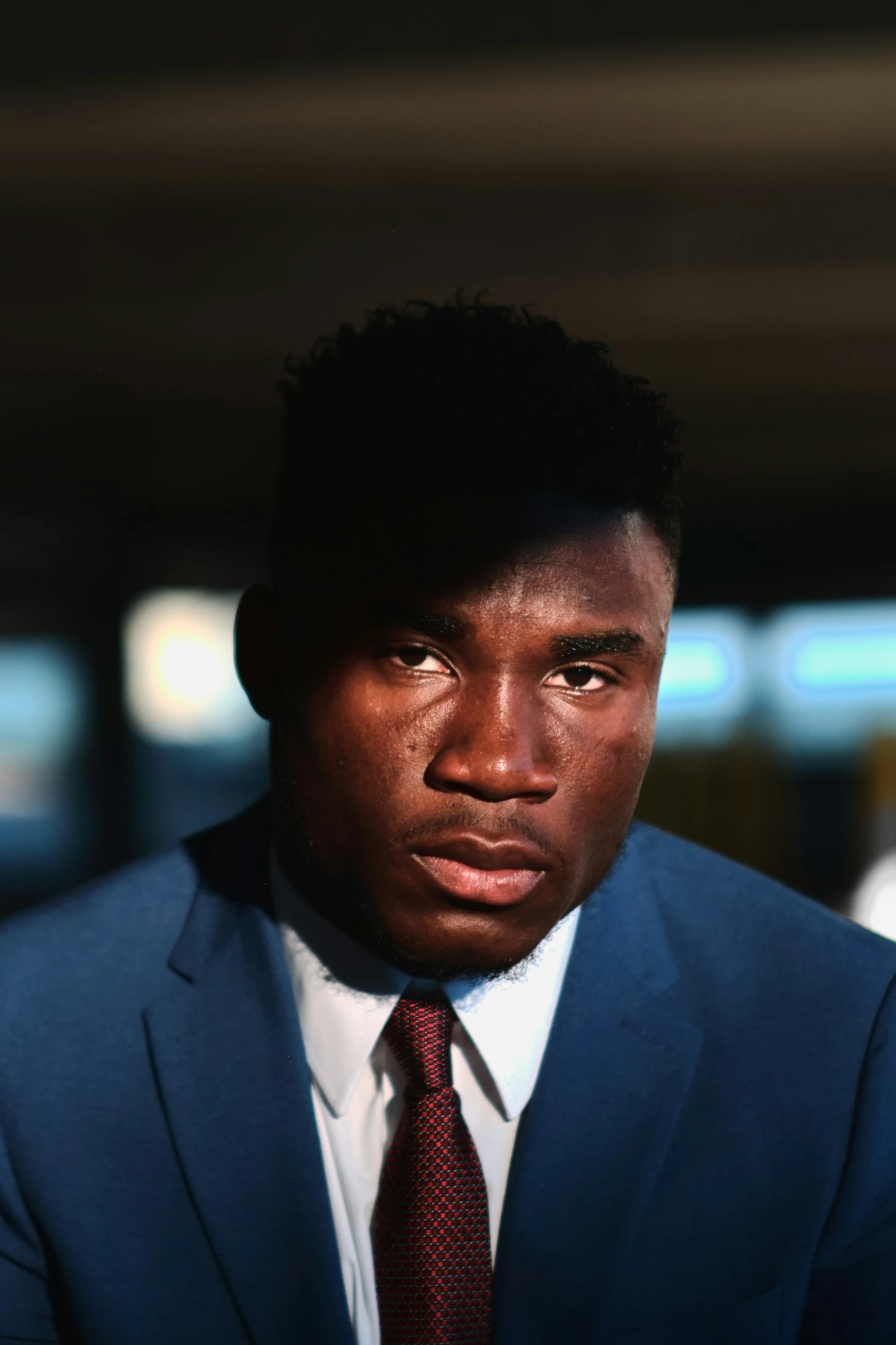 a dark skinned man in a blue suit and red tie