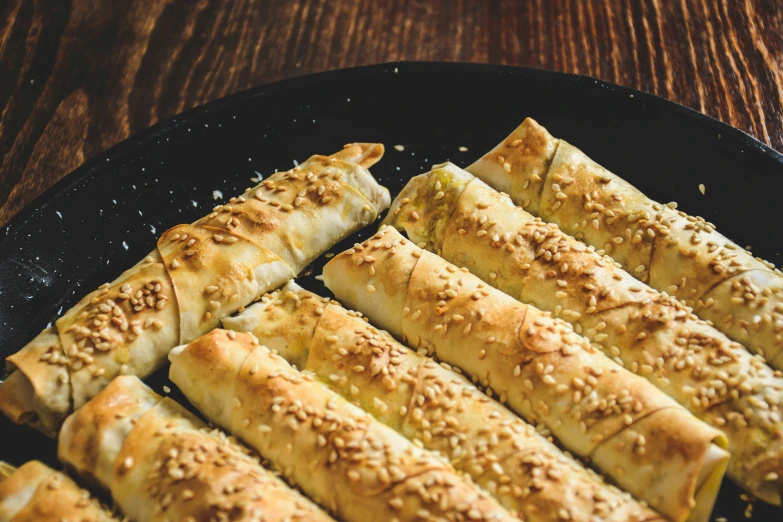 rolls on the black plate are covered in sesame seeds