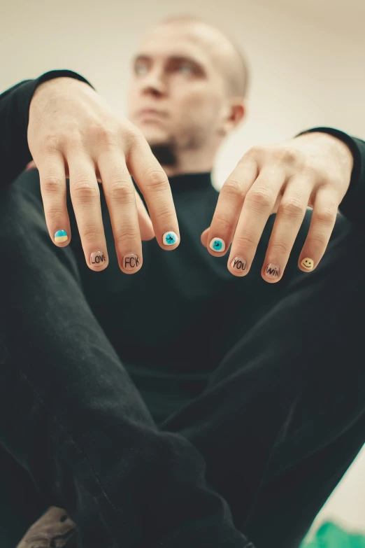 person sitting down and showing his fingers with blue stones