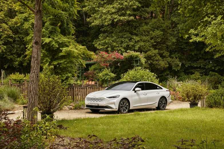 a white car sitting in front of trees and grass