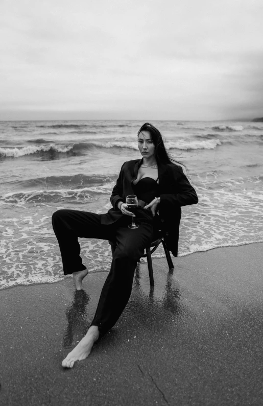 a woman sits in a chair in front of the ocean on the shore