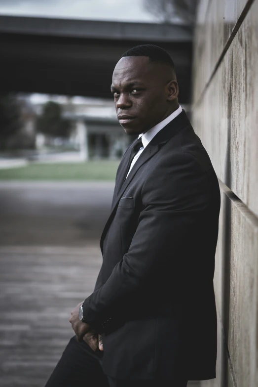 a man in a suit is leaning up against a wall