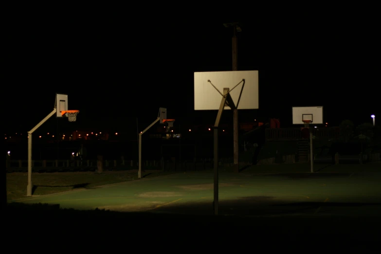 an empty basketball court at night in front of a large building