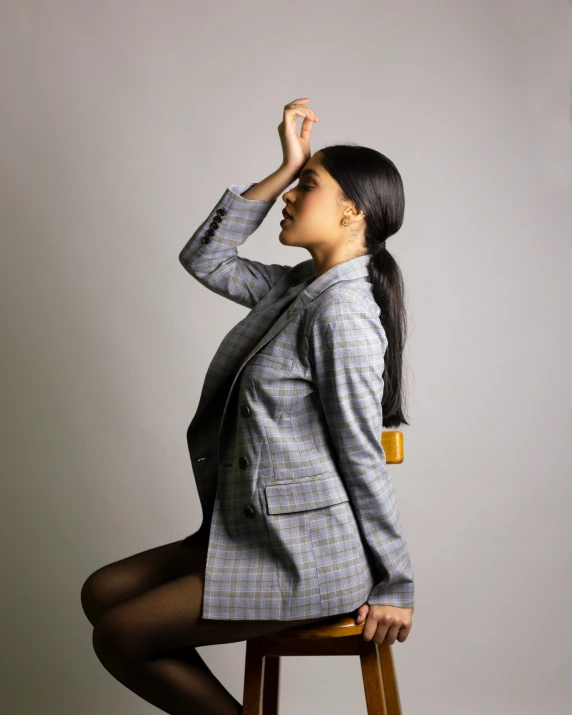 woman sitting on stool with her hand on her forehead