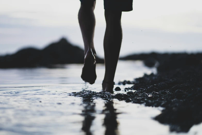 a person walking on the sand with his shoes on