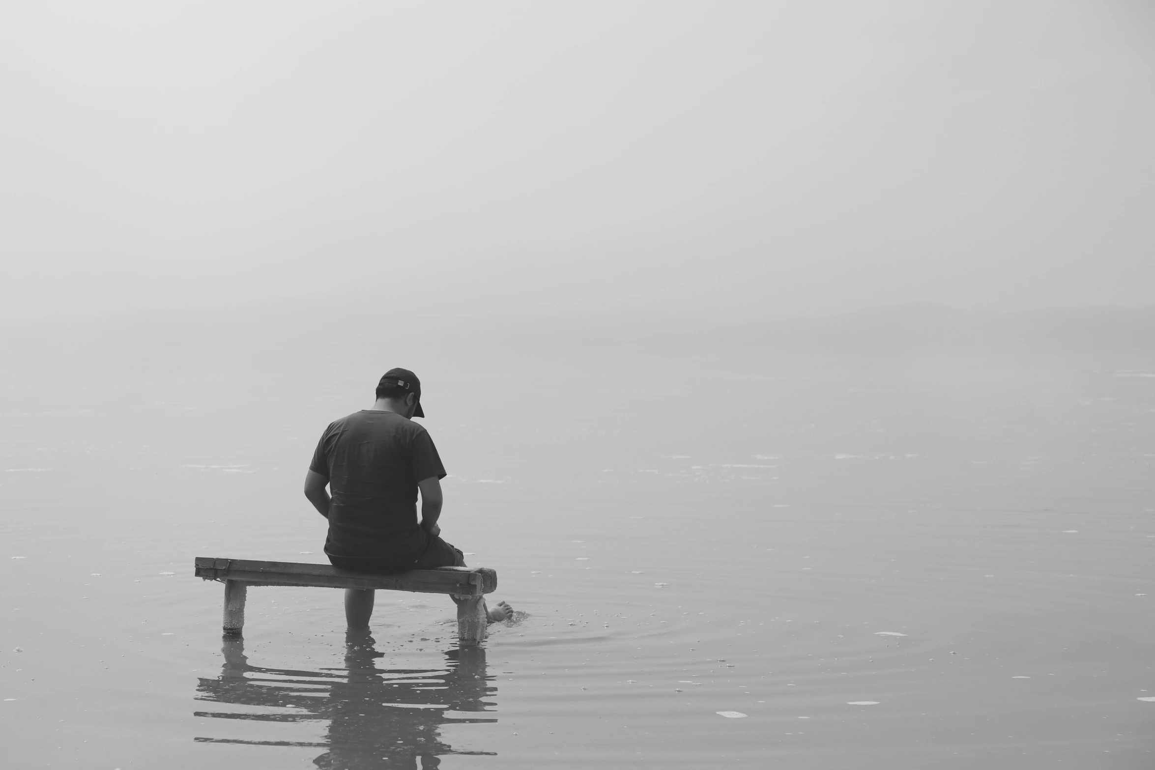 man sitting on a bench in a body of water