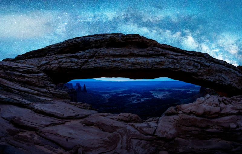 there is a cave in the rocks and has some sky above it