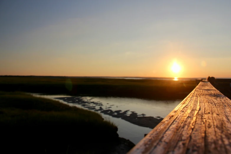 the sun is setting on a long wooden dock