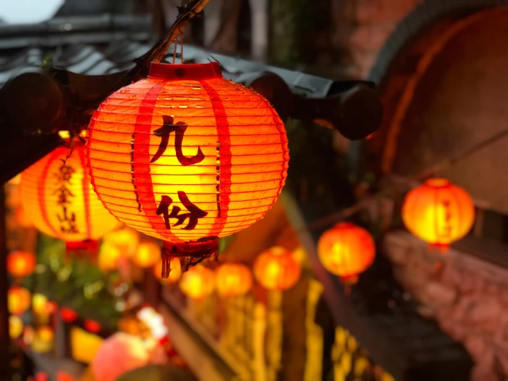many lanterns with asian writing are lit up in a room