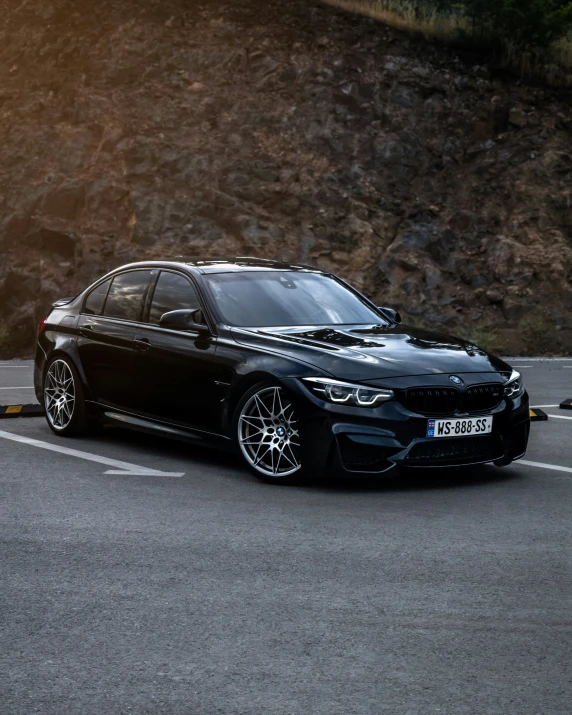 the black bmw is parked next to a rocky area