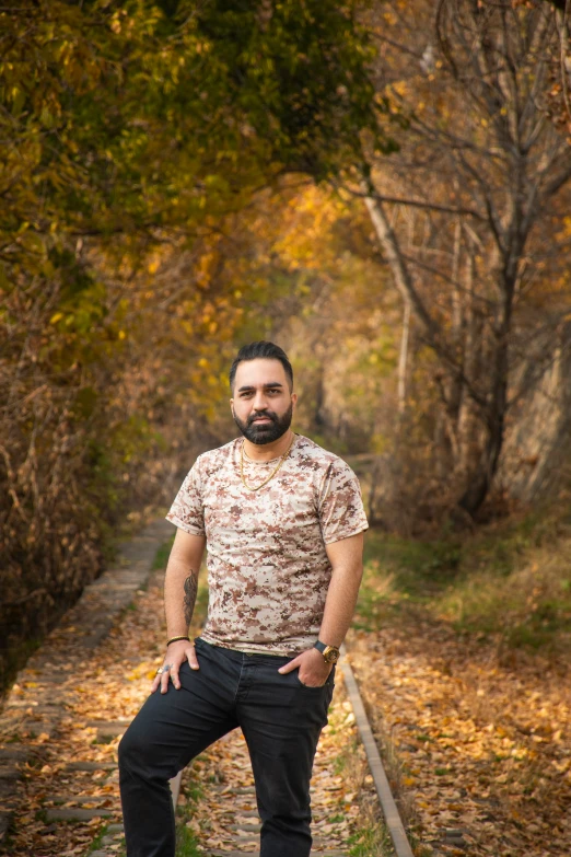 a man posing in front of trees and leaves