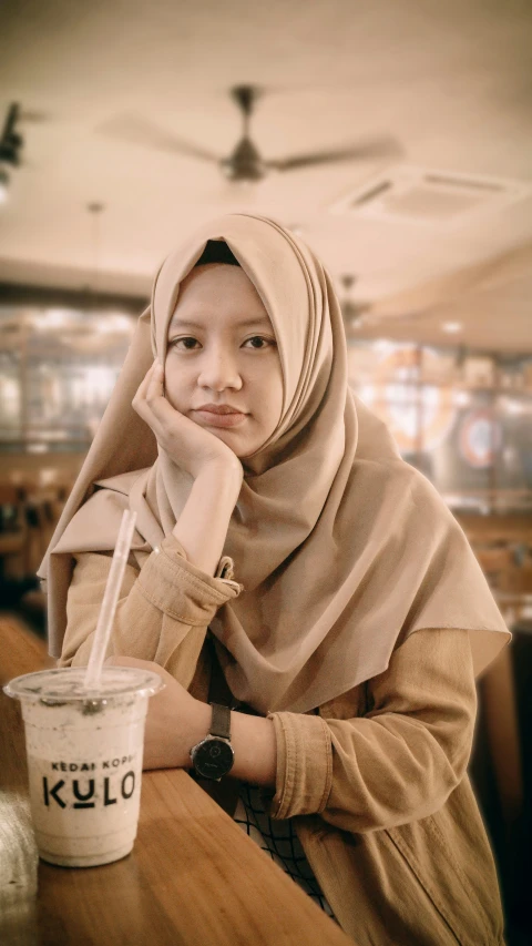 a girl with her hand under her head sitting at a table