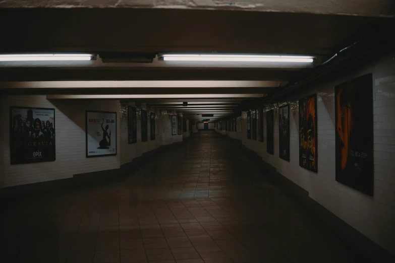 the long corridor with posters is dimly lit