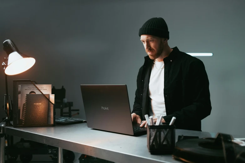 a man in winter hat works on his laptop computer