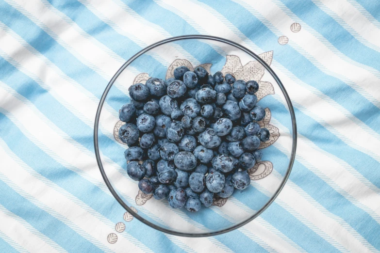 blueberries in a bowl sitting on top of a table