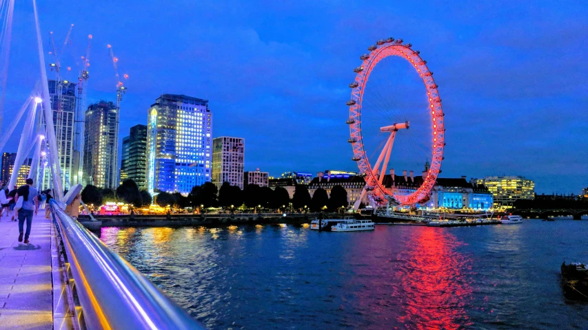 a ferris wheel sitting on the side of a river