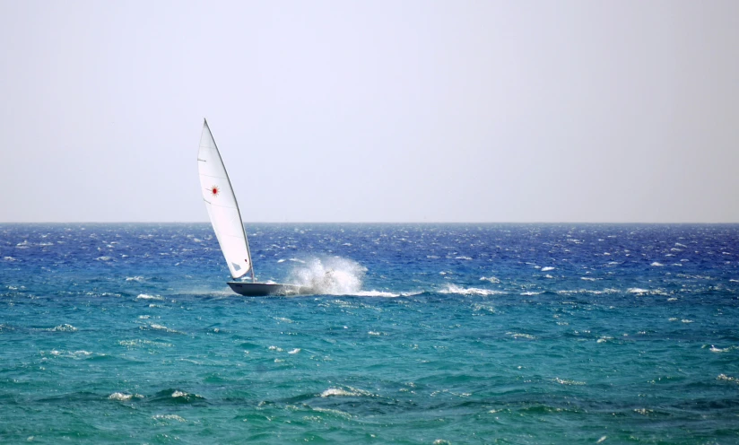 a small sail boat out on the open ocean