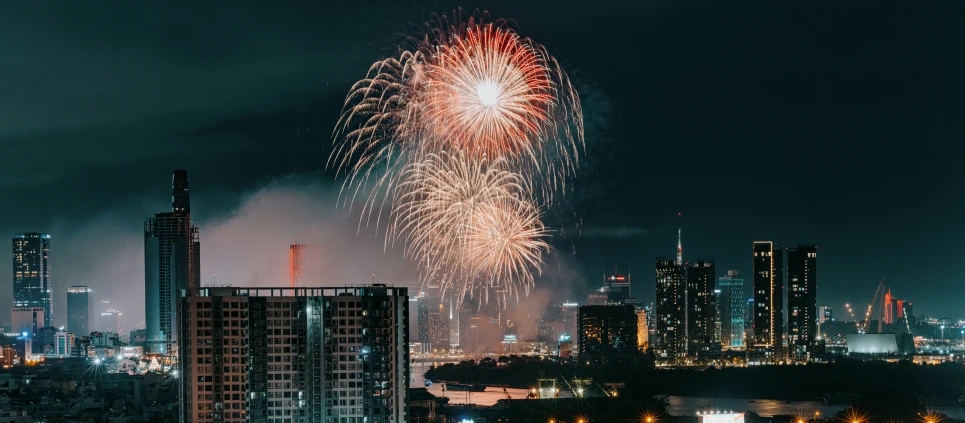 fireworks explode up the sky during the night above a city skyline