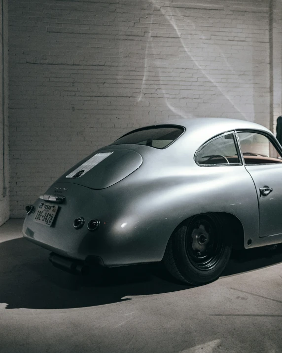 an old silver sports car in a garage