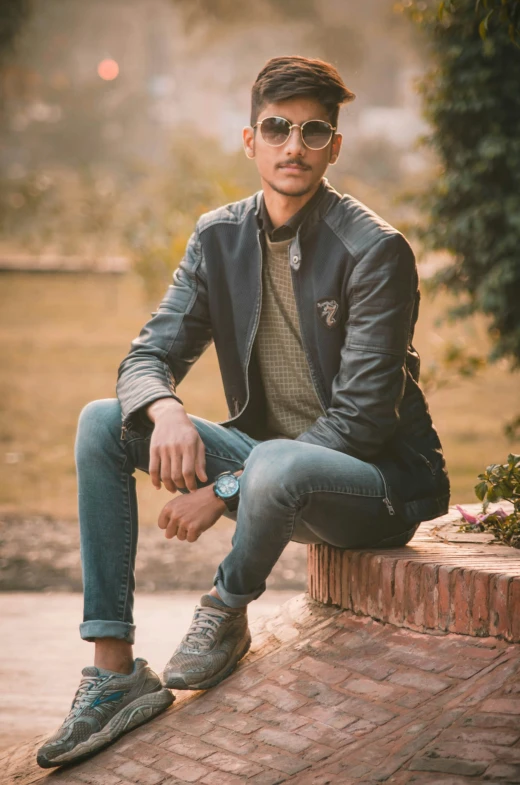 a man with sunglasses sitting on top of a wall